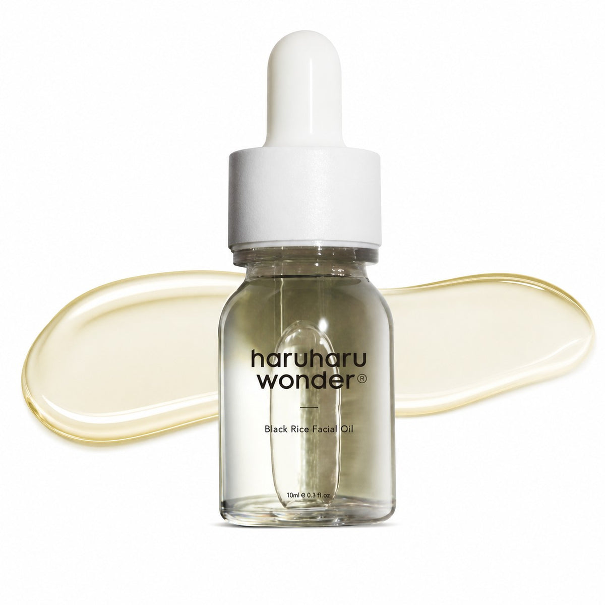A 5ml dropper bottle of Haruharu Wonder Black Rice Facial Oil, featuring a clear glass bottle with a white dropper cap, set against a white background with a decorative smear of the pale yellow oil behind it.
