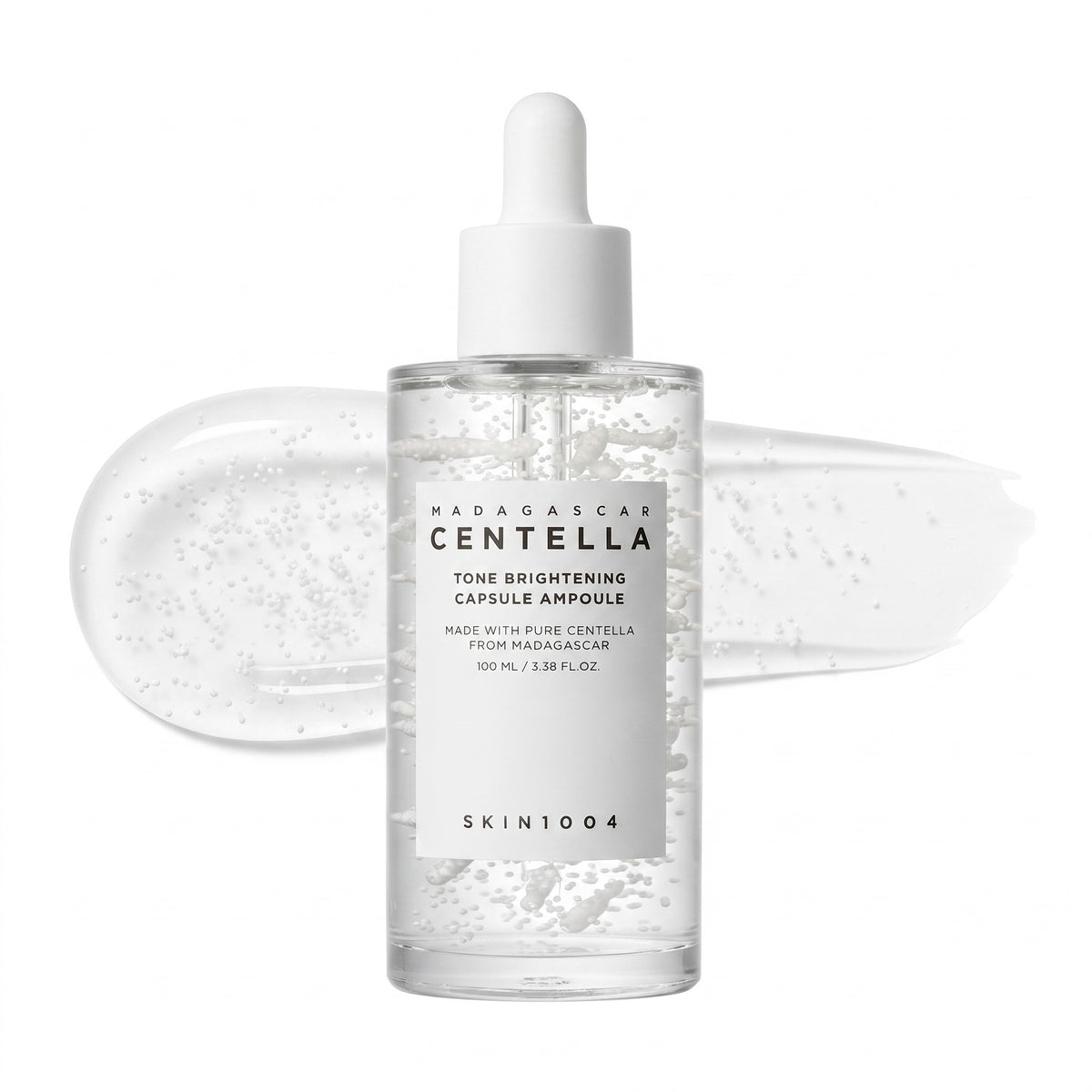 A clear glass dropper bottle of SKIN1004 Madagaskar Centella Tone Brightening Capsule Ampoule with a white dropper cap, shown against a white background with a translucent gel swatch behind it.